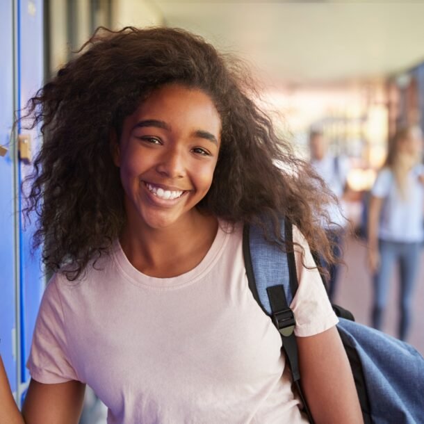 Portrait of black teenage girl by lockers in school corridor